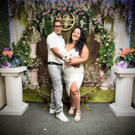 A joyful wedding celebration with guests holding flowers and cheering outdoors. Seasoned Celebrant.